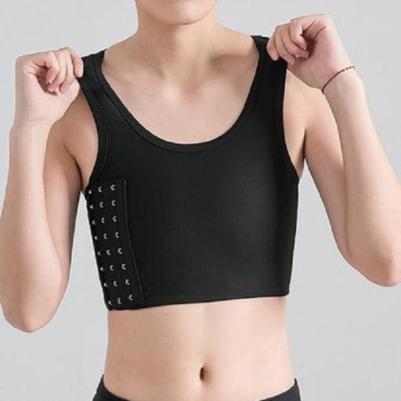A person is wearing a black breathable chest binder with side buckles, in a standing position.