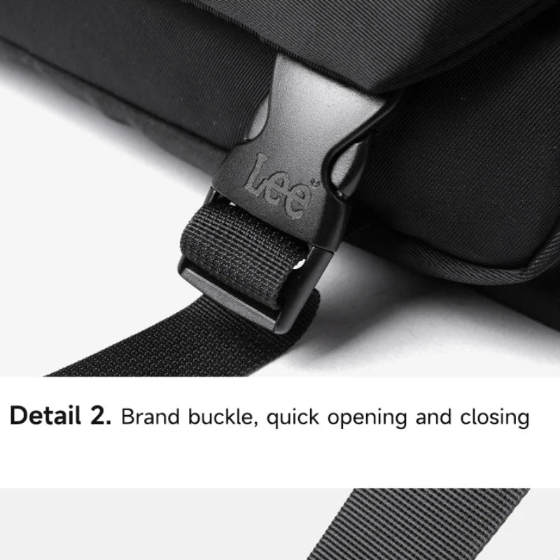 Close-up of a black bag with a brand buckle and adjustable shoulder strap on a white background.