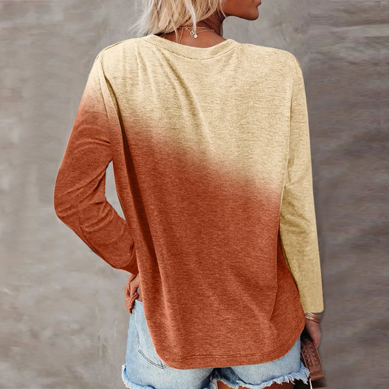Person wearing a long-sleeve shirt with a gradient design from yellow to orange, standing against a neutral background.