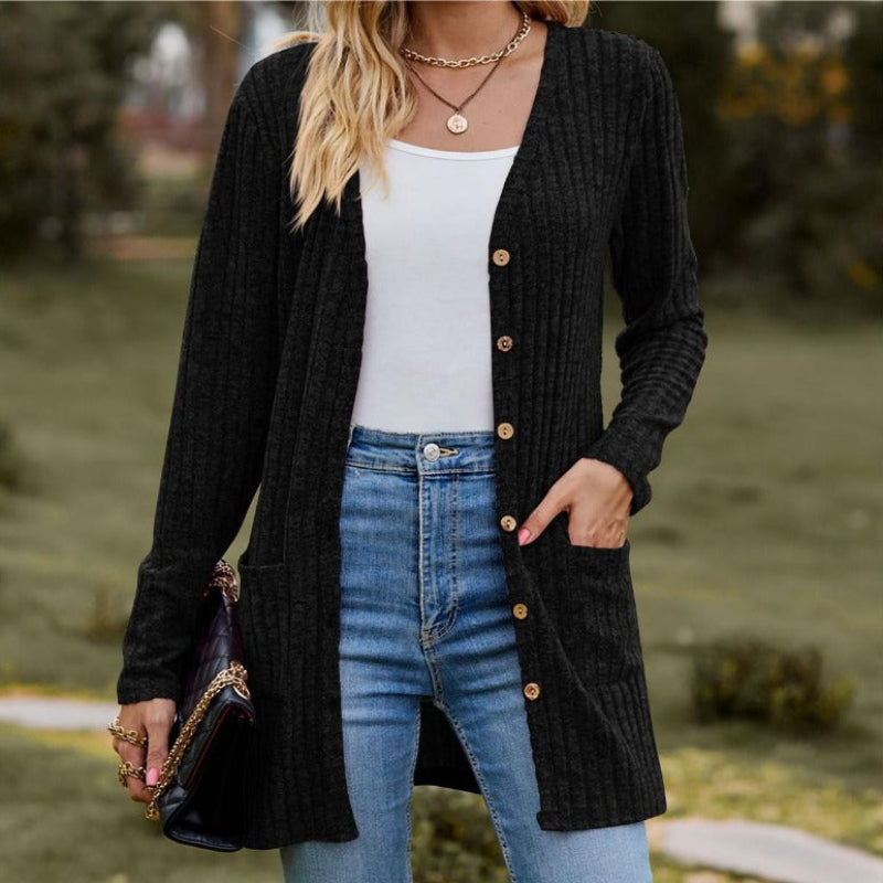 Person wearing a black cardigan, white top, and blue jeans outdoors.