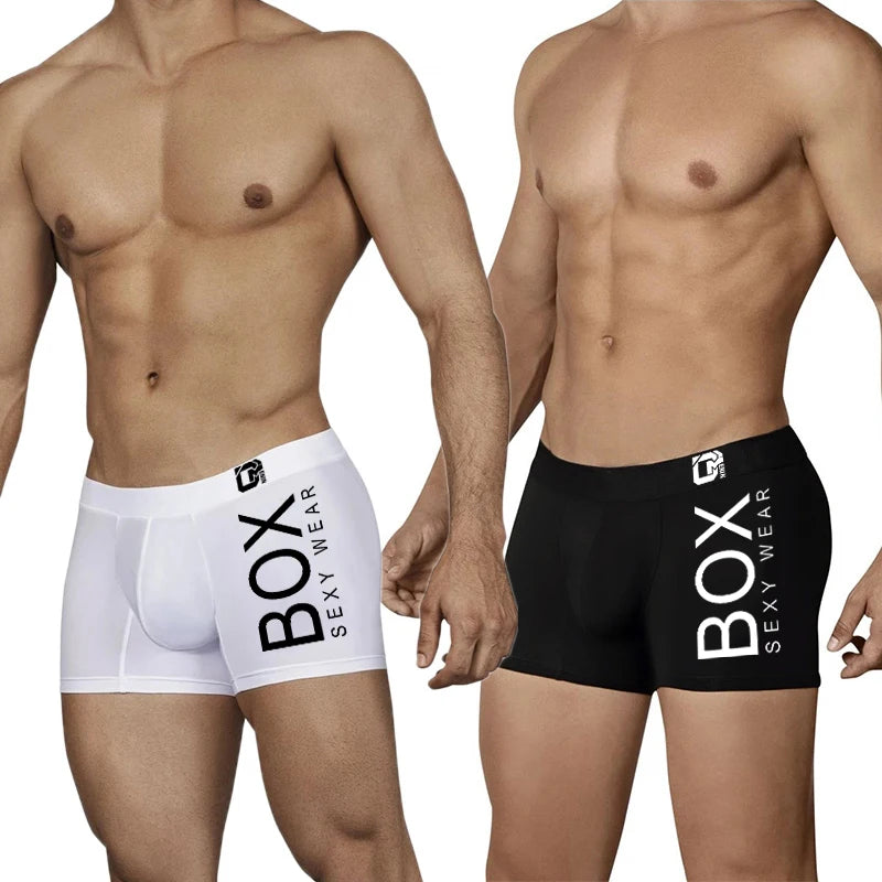 Two men wearing Box Sexy Wear boxer briefs, one white and one black, on a plain background.