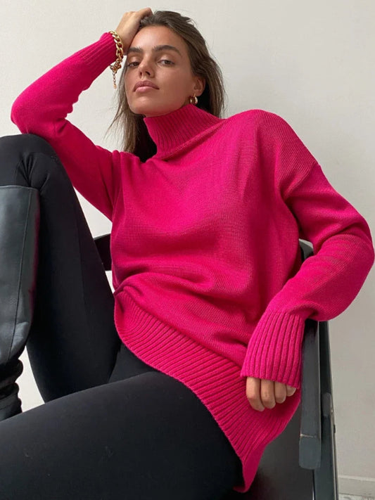 Woman wearing a bright pink sweater sitting on a chair with a plain background