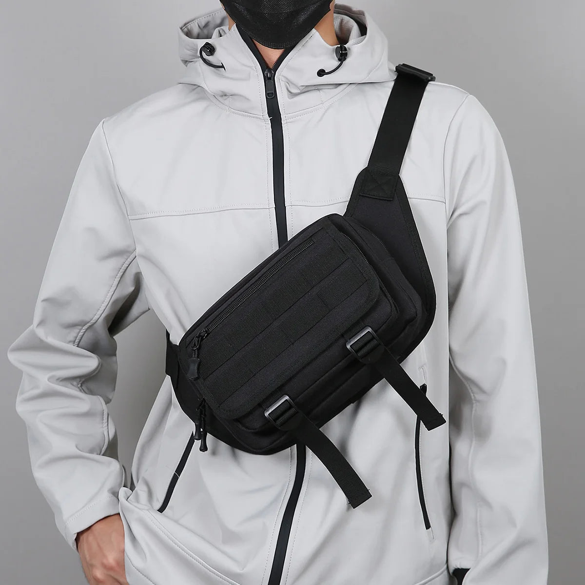 Person wearing a black crossbody bag over a gray background