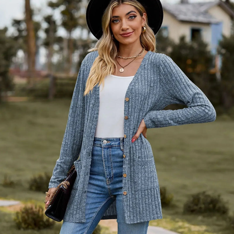 Woman wearing a blue cardigan, white top, and jeans outdoors.